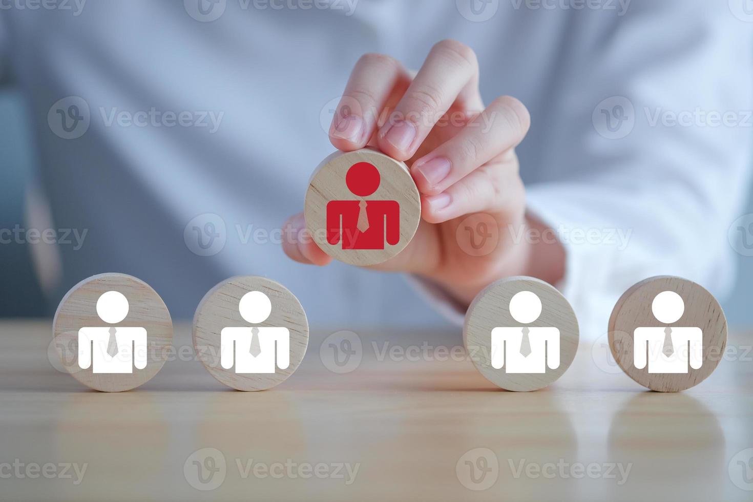 Business hiring and recruitment selection. Career opportunity. Human Resource Management. finding human. Hand choosing red business man icon on wooden block. Choice of employee leader from the crowd. photo