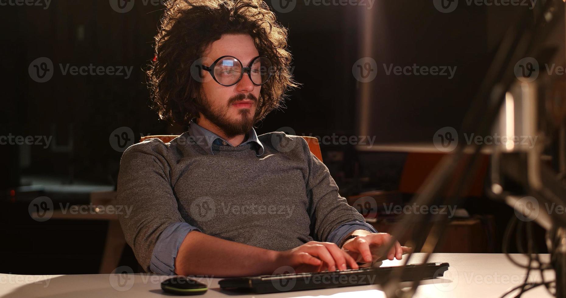 man working on computer in dark office photo