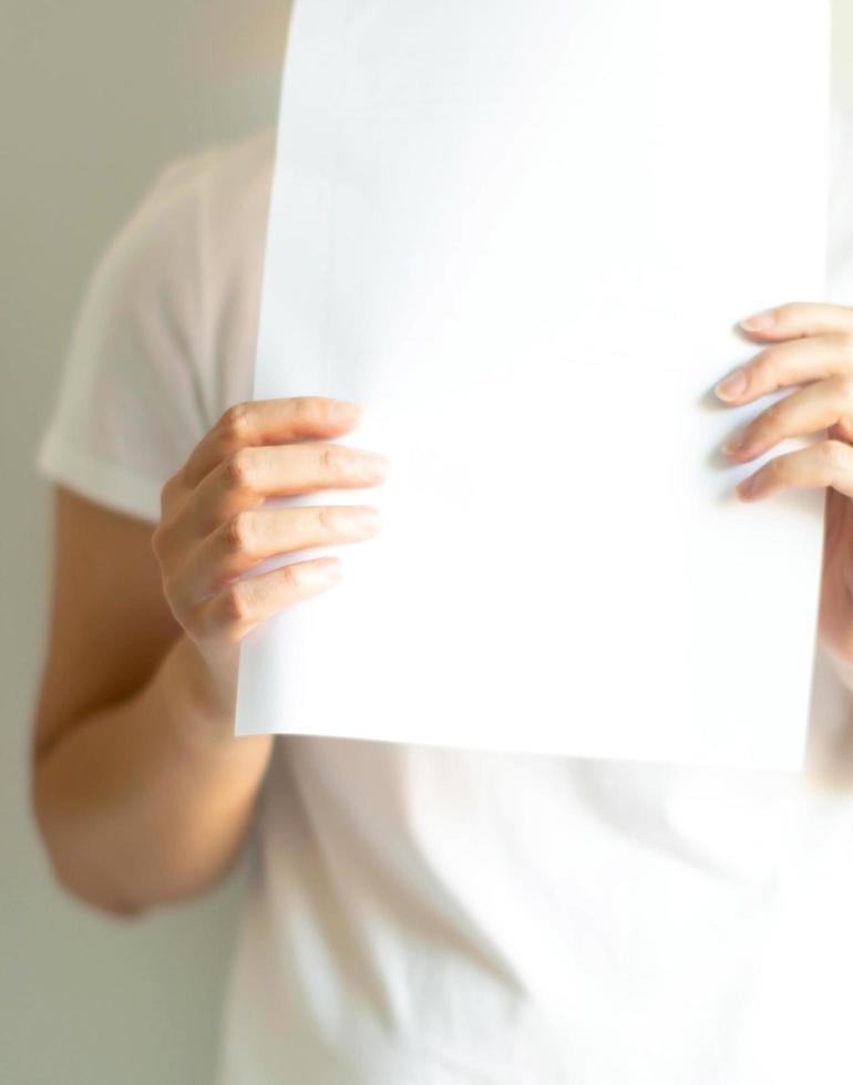 Close up of a woman in casual showing an empty white paper, advertisement concept. photo