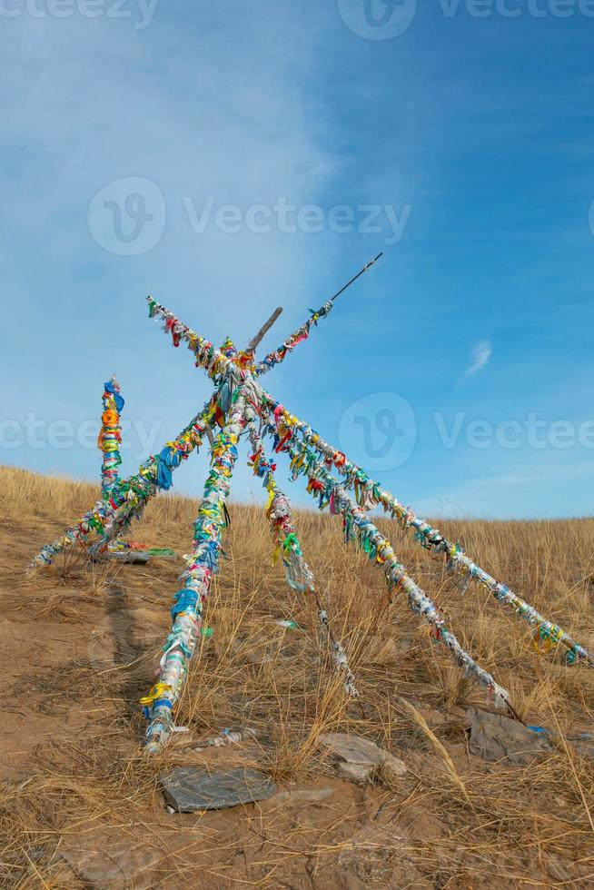 shaman wood that lean against in triangle tied with many of colorful ribbons, religion belief. photo