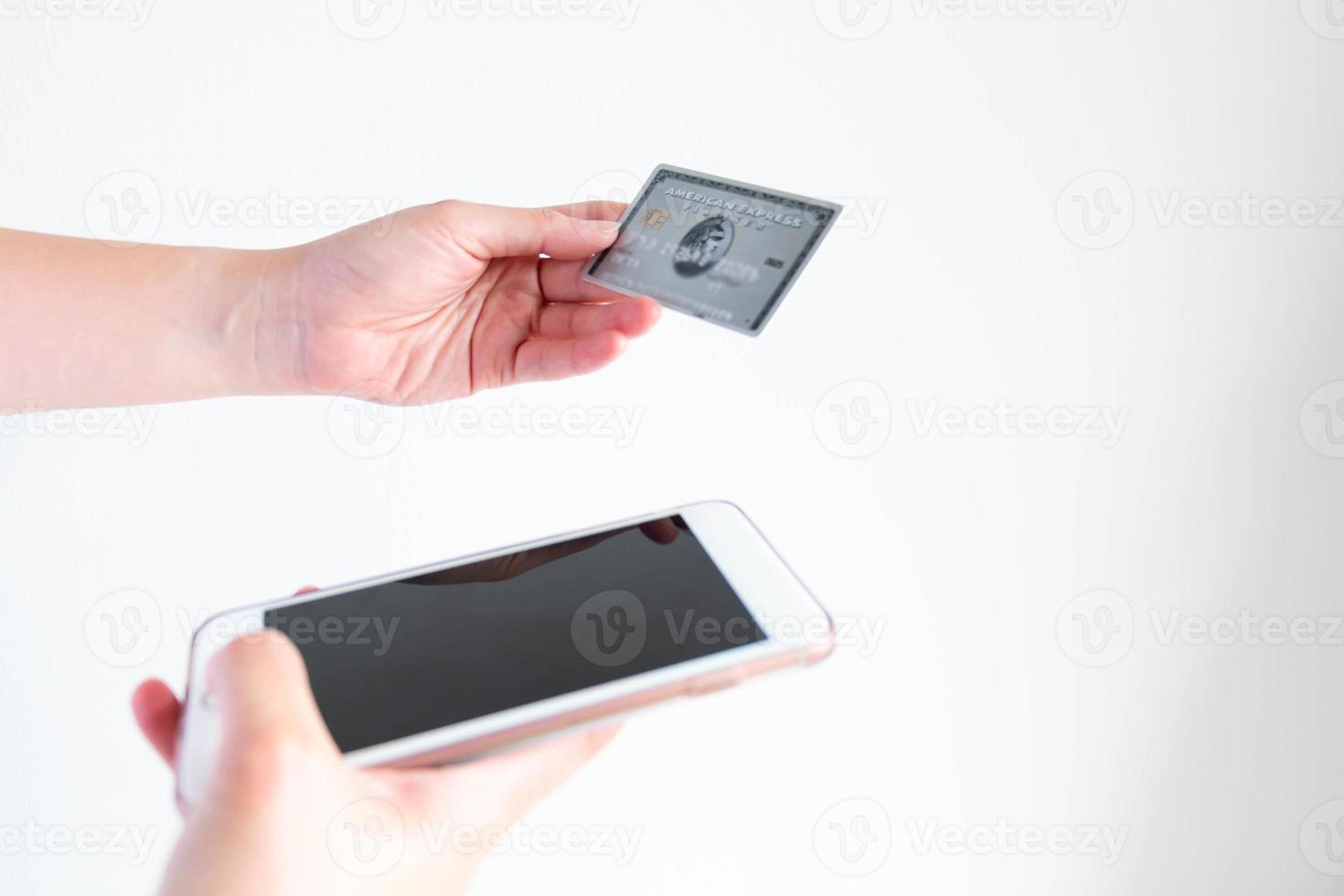 una persona que tiene una tarjeta de crédito american express para comprar en línea a través de un teléfono móvil. foto