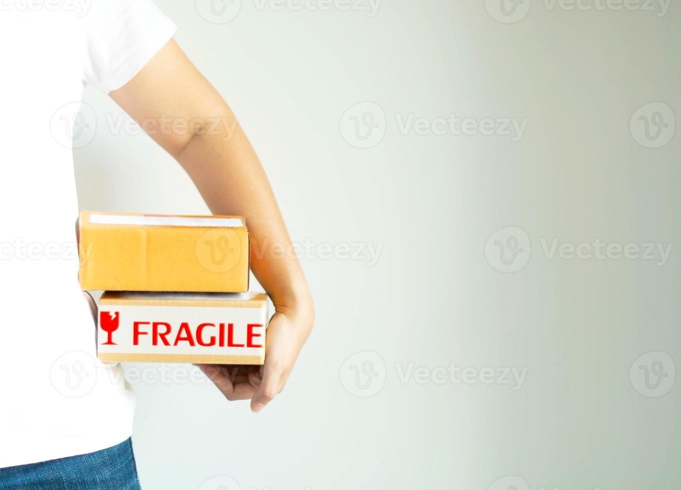 A hand of woman in white T-shirt holding two post boxes at the side on a white background. photo