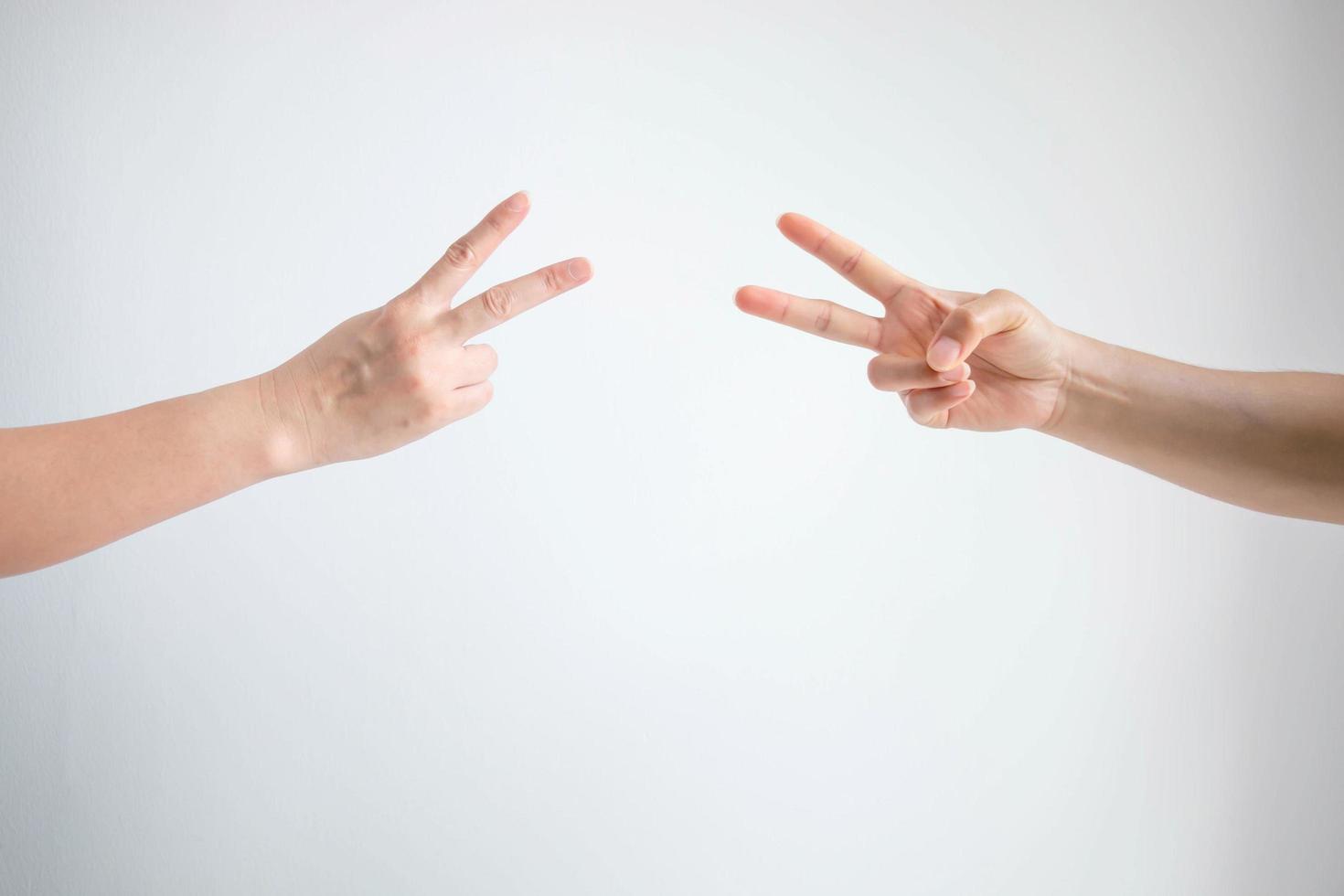 dos personas jugando tijeras de papel de piedra con ambos símbolos de tijeras de postura sobre fondo blanco. foto