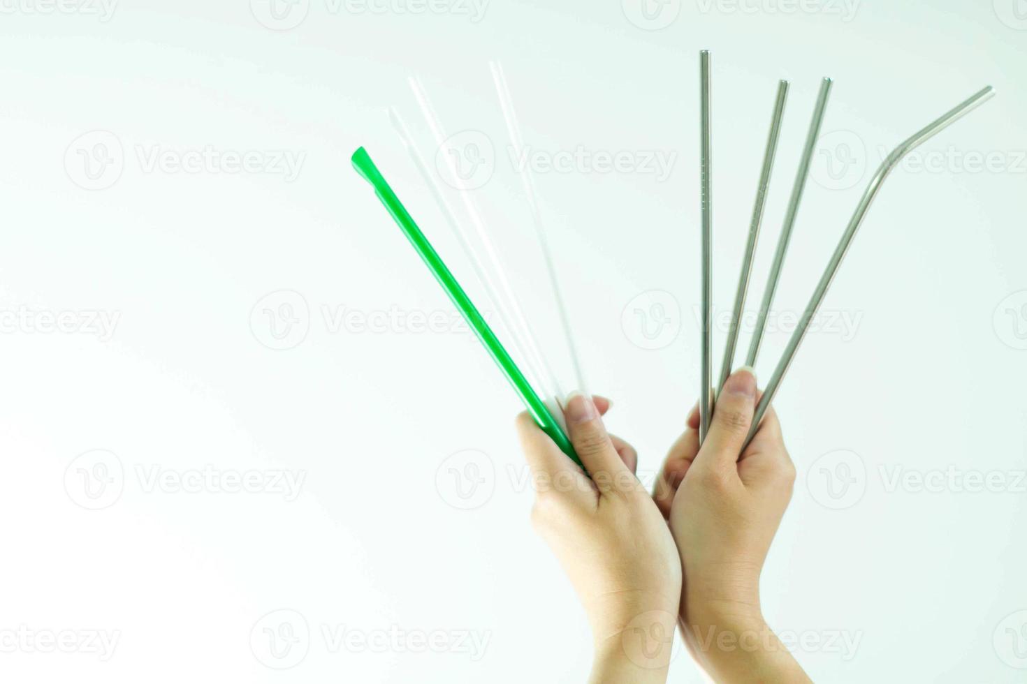 Hands hold plastic straws vs stainless straws on white background. photo