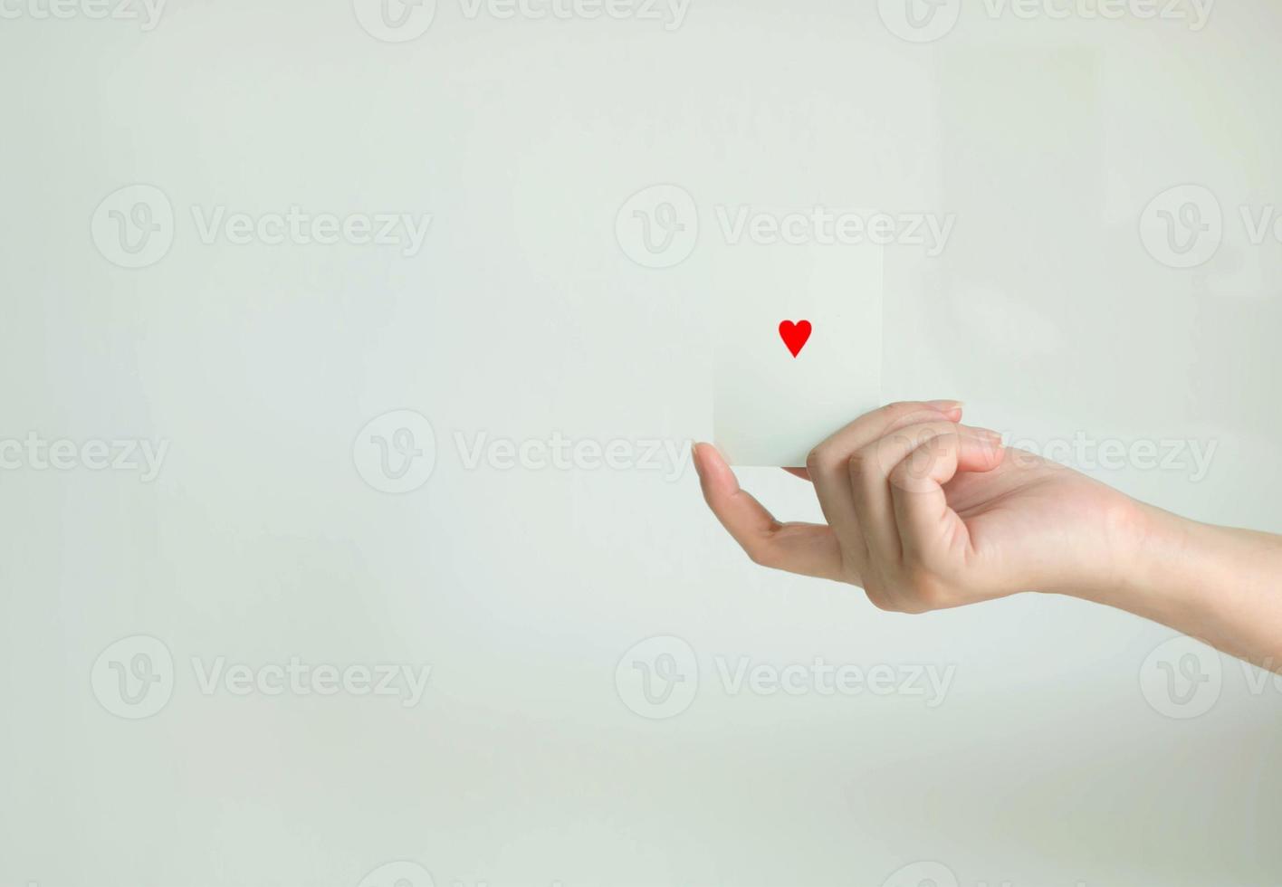 Isolated image of a hand holding and show red heart at center of white card. photo