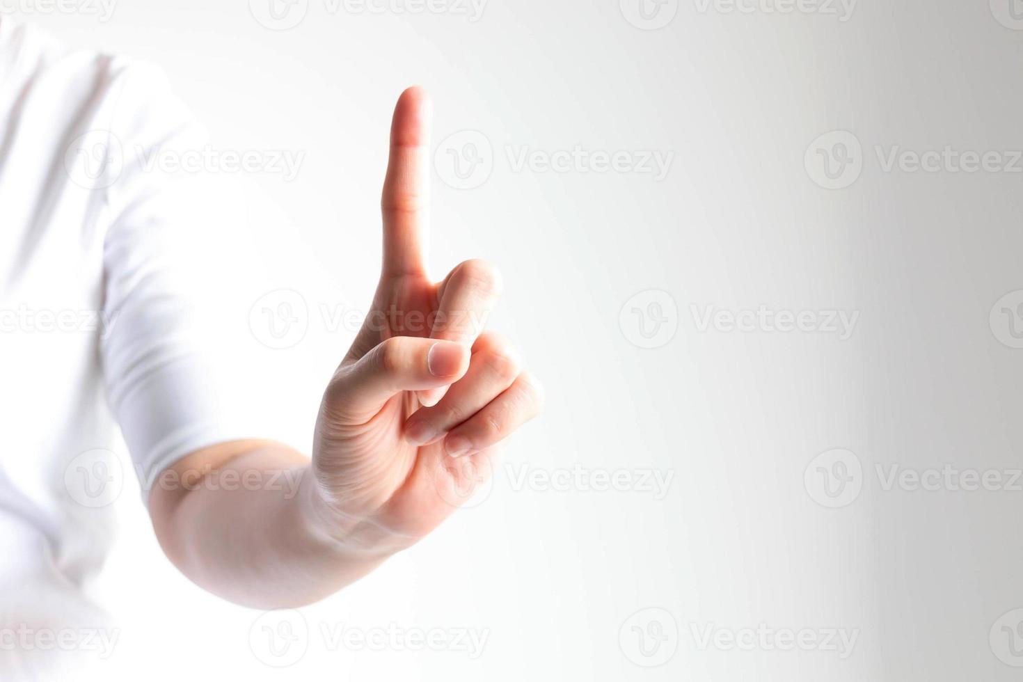 A hand showing number one by raising forefinger in close-up on white background and little light. photo