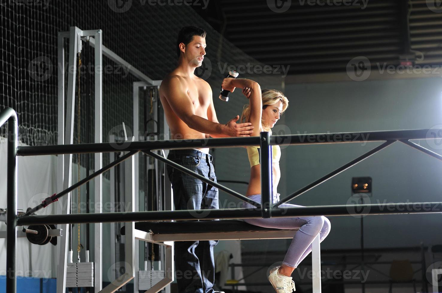 woman in the fitness gim working out with personal trainer photo