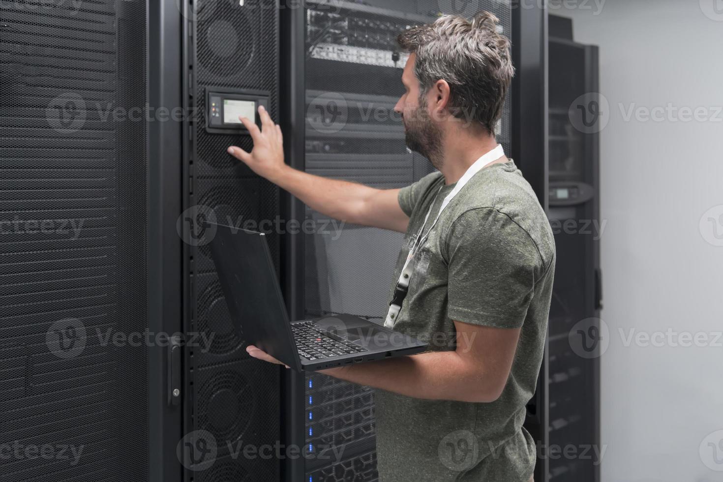 Data Center Engineer Using Laptop Computer Server Room Specialist Facility with Male System Administrator Working with Data Protection Network for Cyber Security or Cryptocurrency Mining Farm. photo