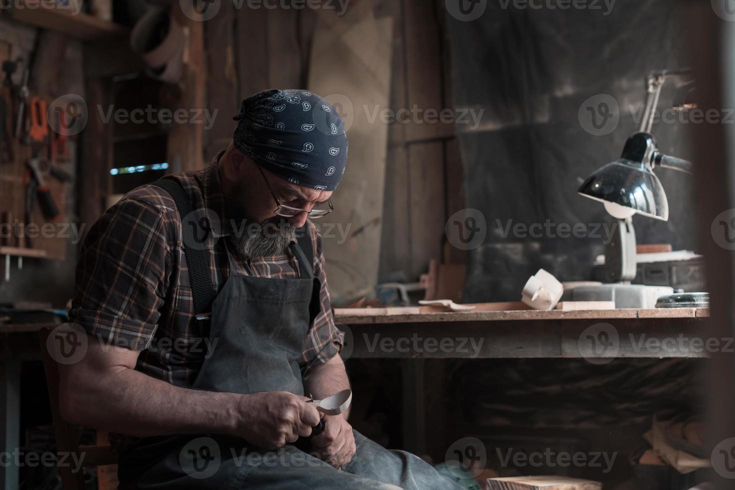 maestro de cucharas en su taller con productos y herramientas de madera foto