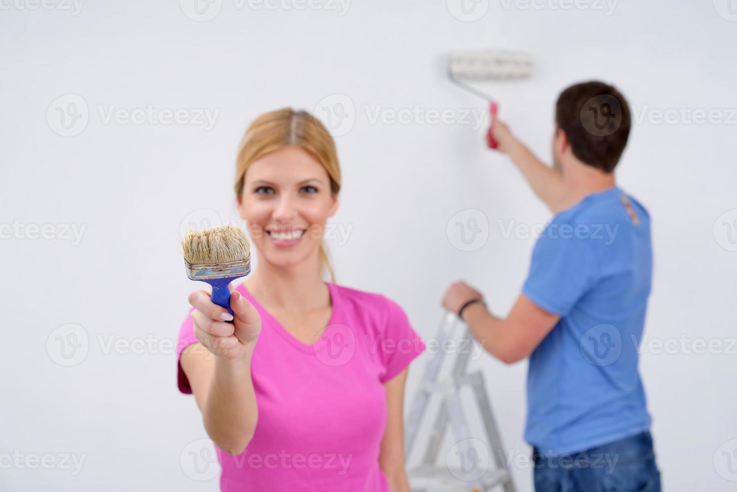 pareja feliz pintando una pared en su nuevo hogar foto