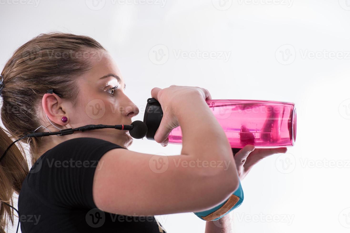 female fitness instructor drinking water from bottle photo