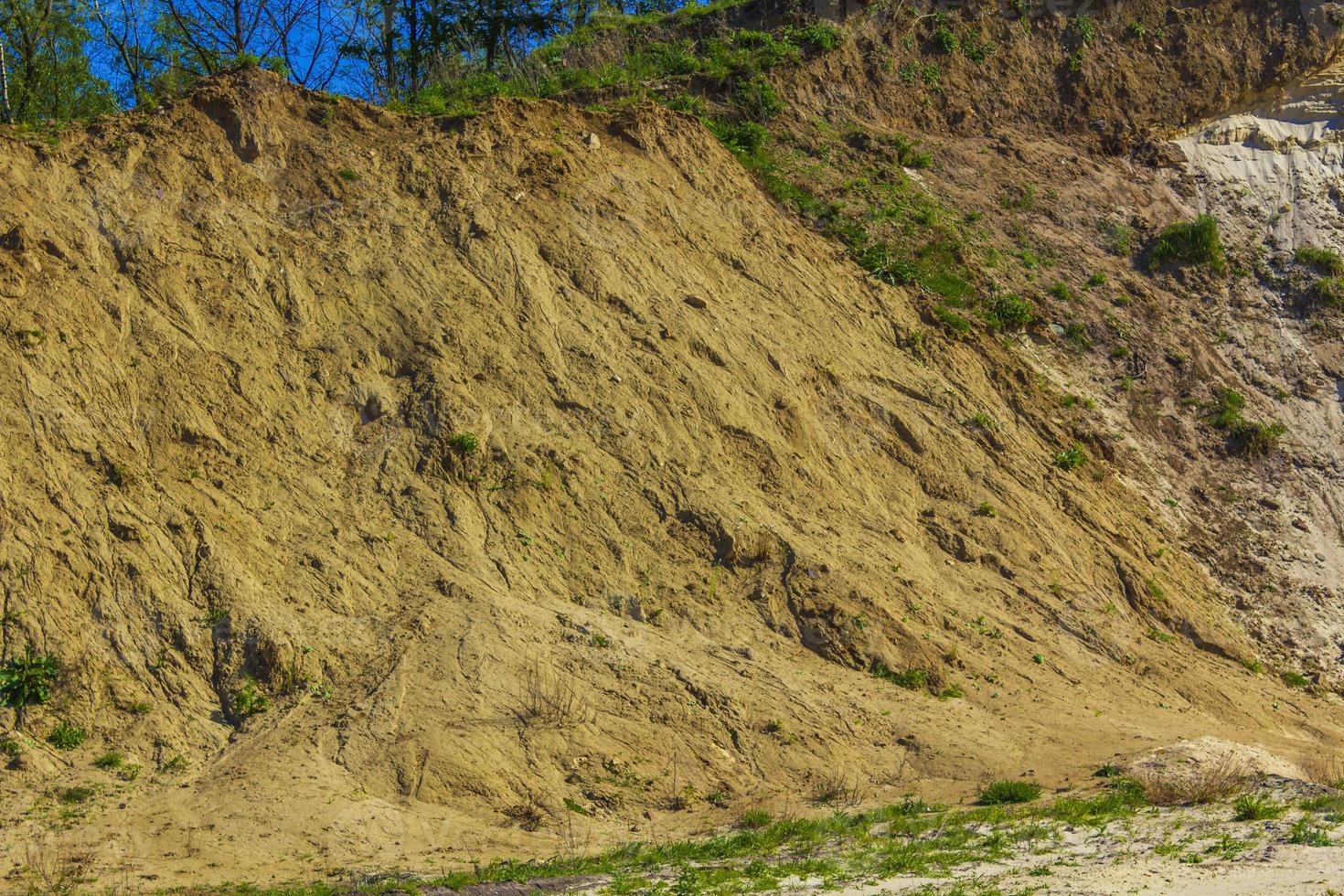 montañas de arena excavadas y pilas de escombros lago de cantera estanque de dragado. foto