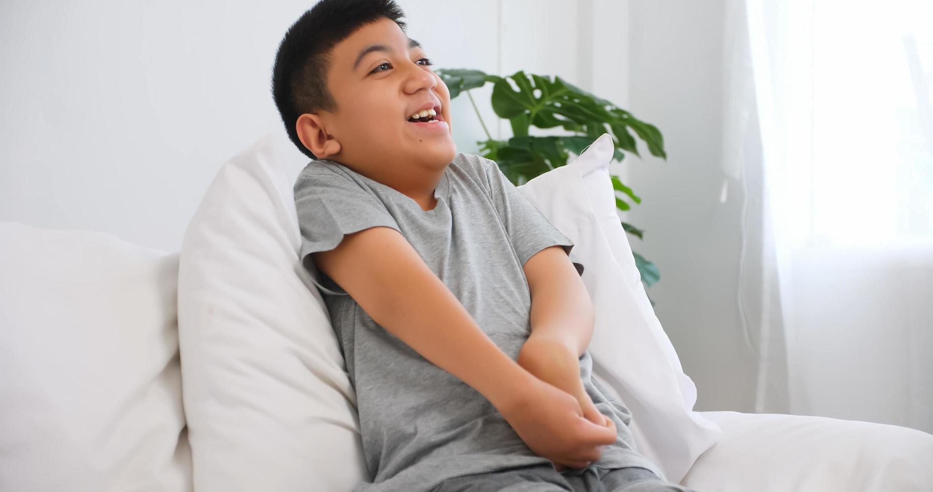 Disabled boy sitting on sofa at home. photo