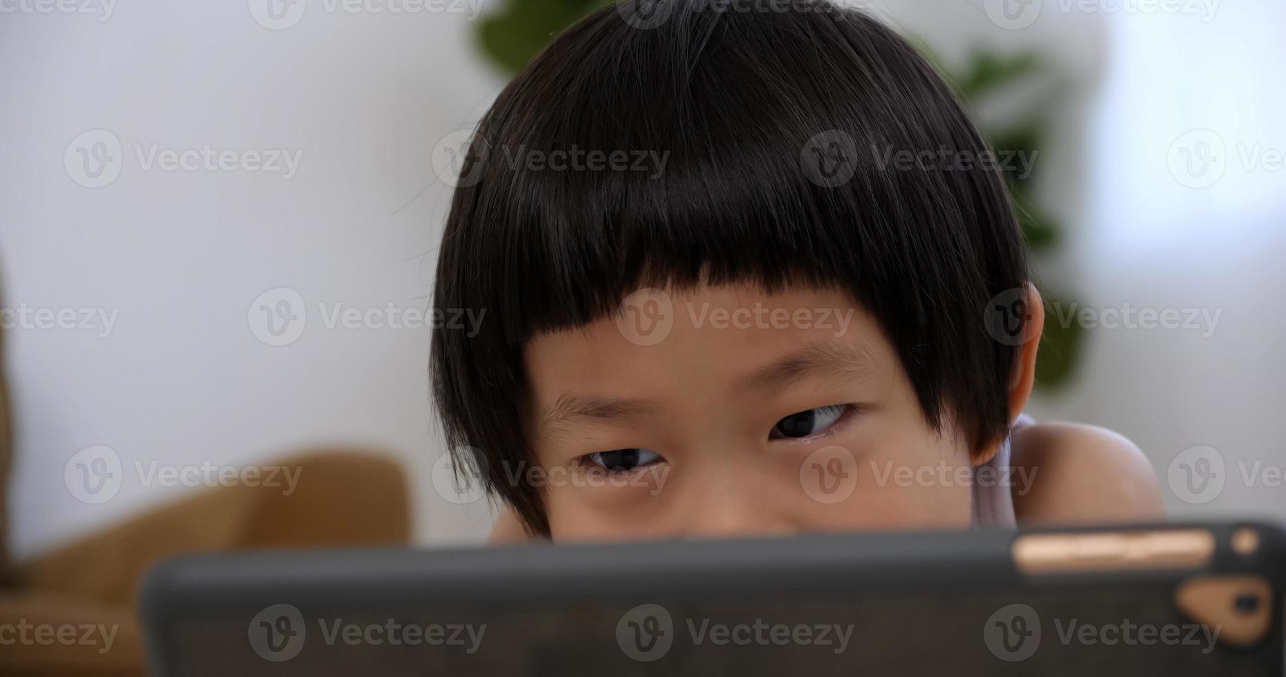 Cute little boy using tablet computer at home. photo