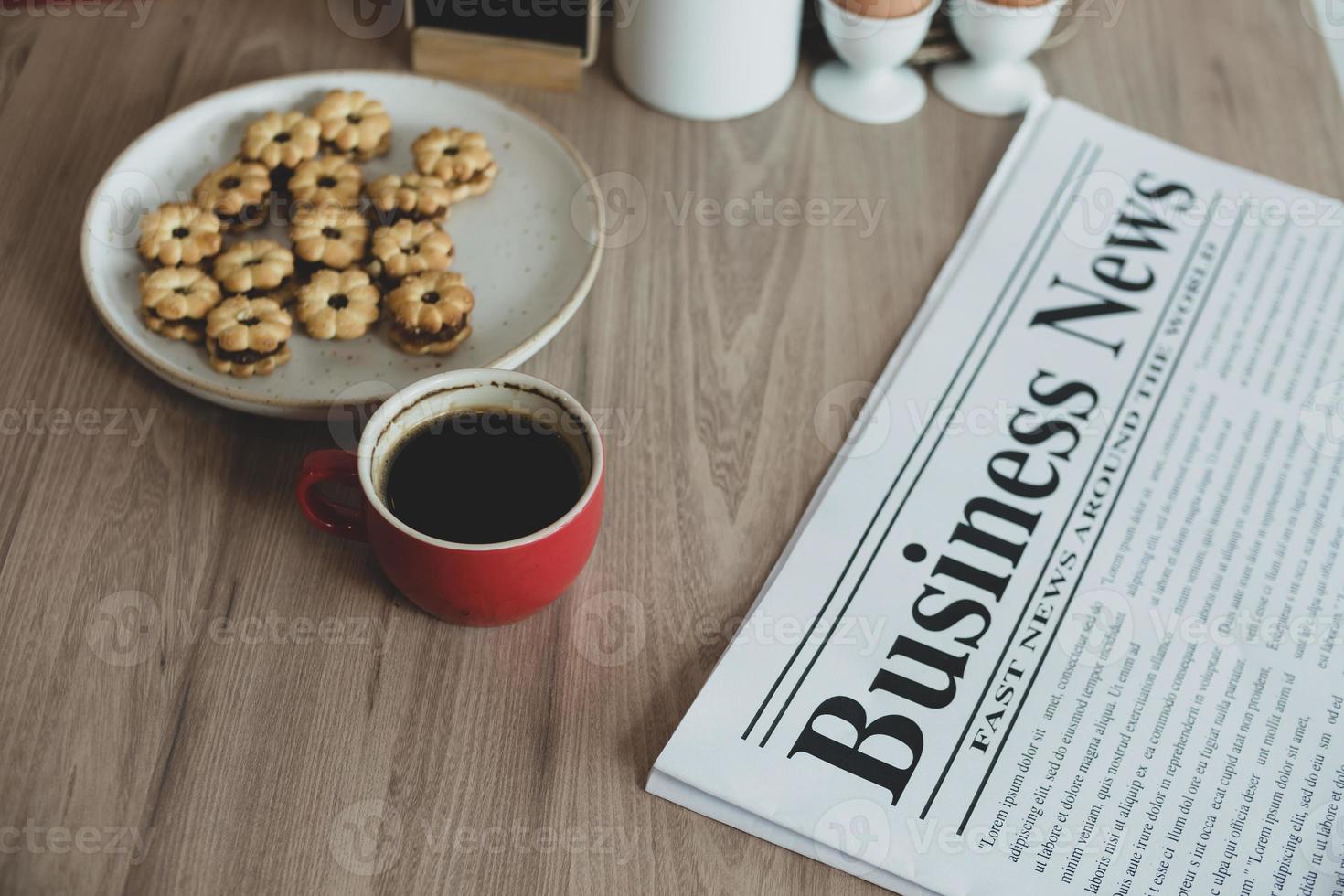 newspaper, a cup of coffee and snacks on a wooden table. photo