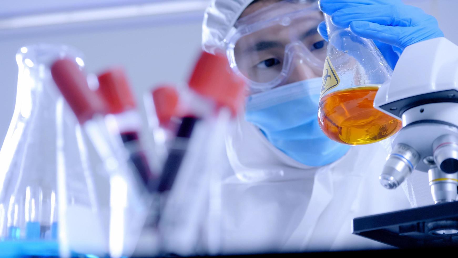 Scientist in PPE suite doing some research checking a liquid in a test tube at laboratory. photo