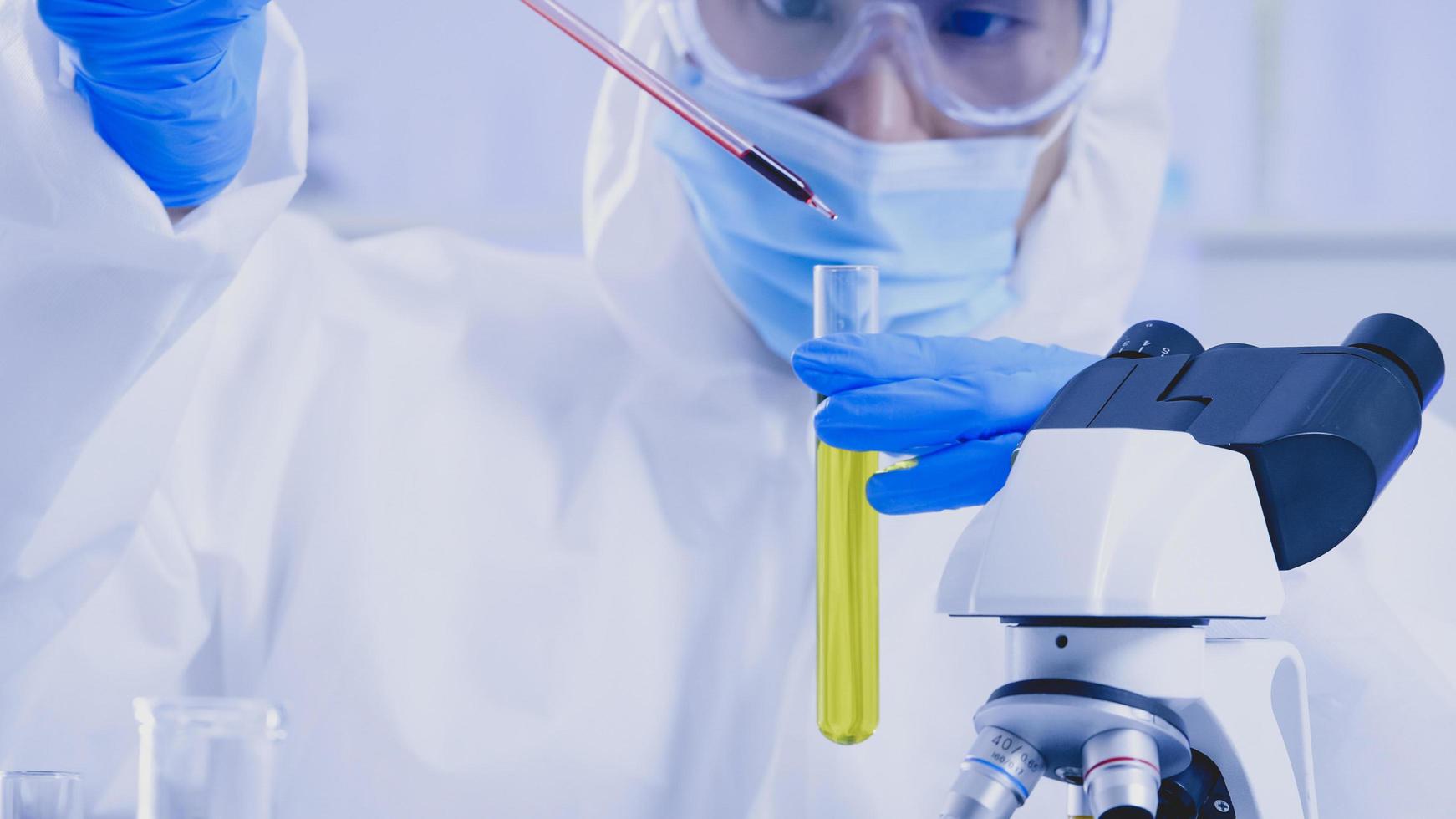 Scientist in PPE suite doing some research checking a liquid in a test tube at laboratory. photo