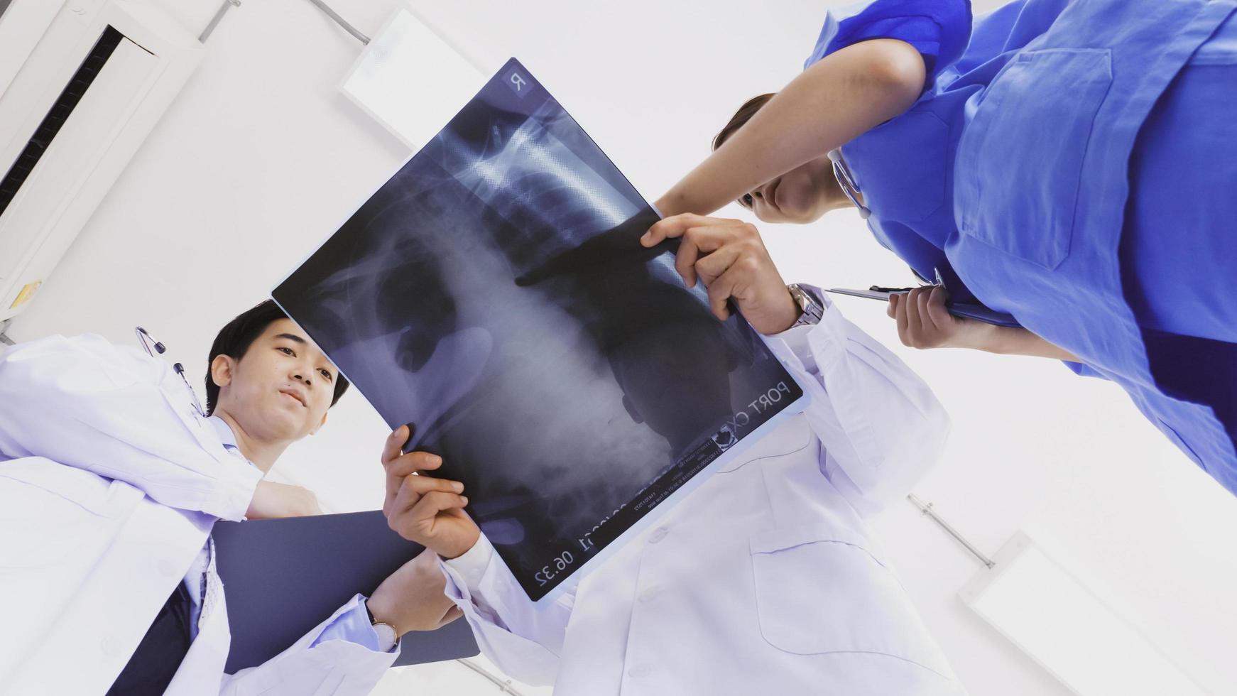Doctor and medical assistants discussing about diagnosis result on x-ray film. photo