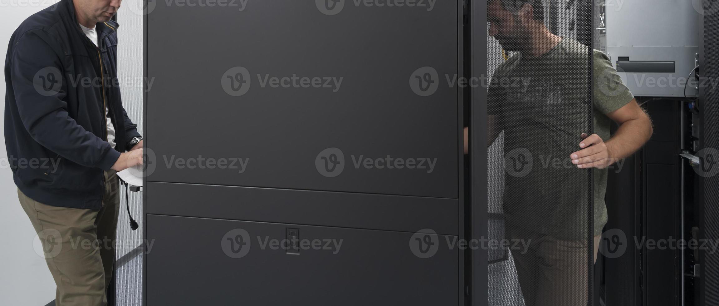 Technicians team updating hardware inspecting system performance in super computer server room or cryptocurrency mining farm. photo