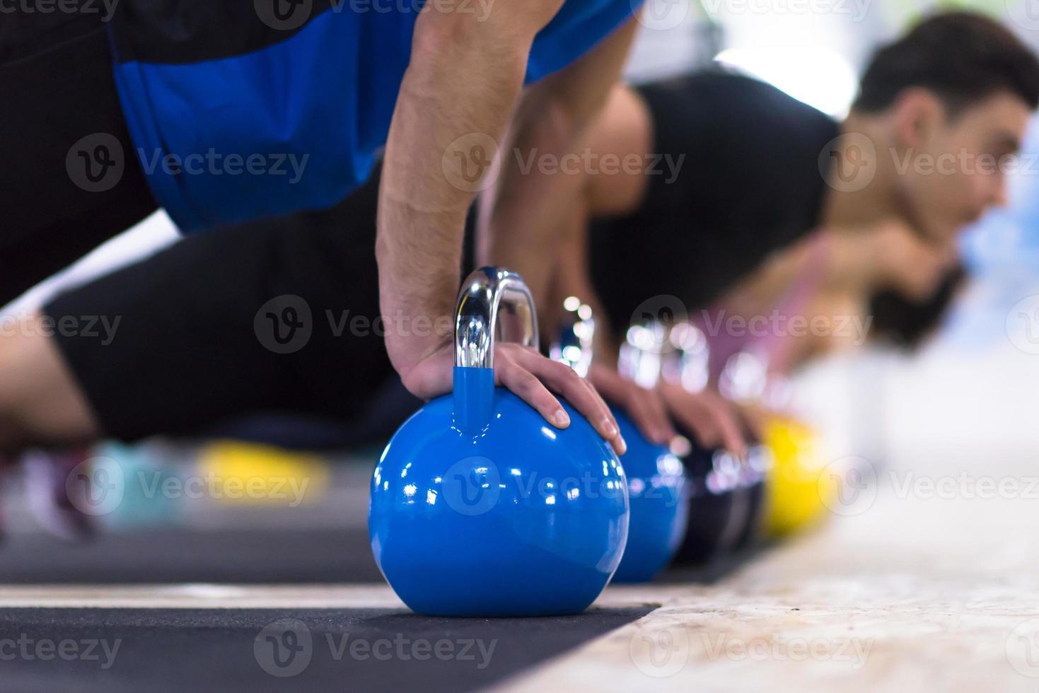 young athletes doing pushups with kettlebells photo