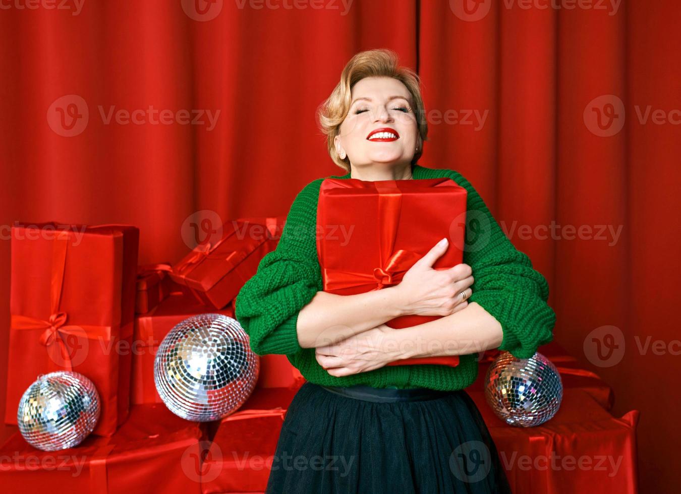 mature stylish elegant woman with gift box on red background. Party, fashion, celebration, anti age concept. photo