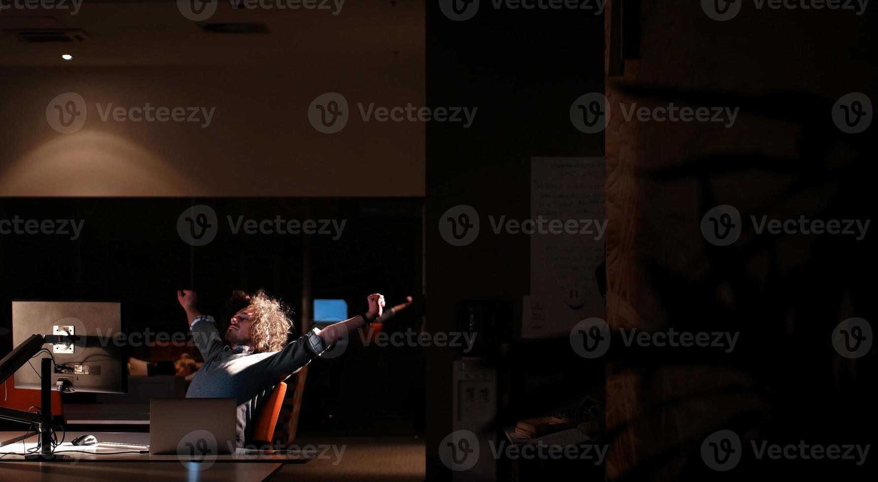 man working on computer in dark office photo