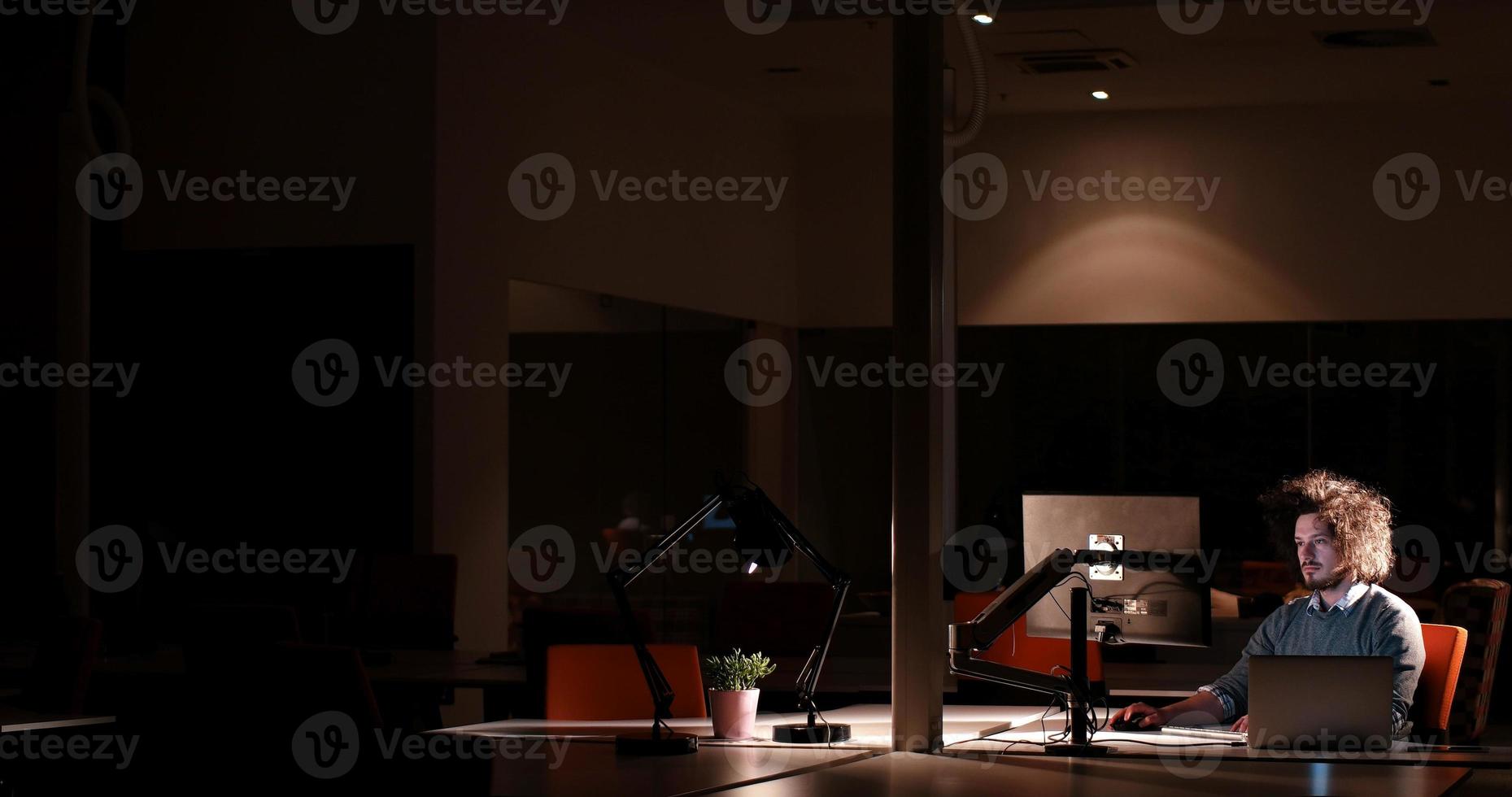 man working on computer in dark office photo