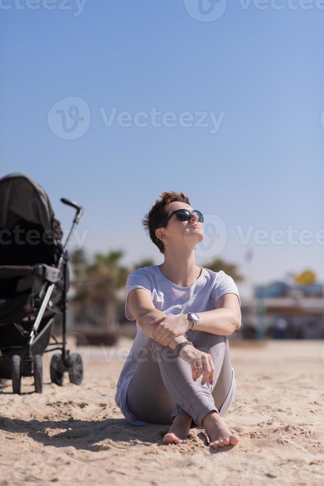 Young mother with sunglasses relaxing on beach photo