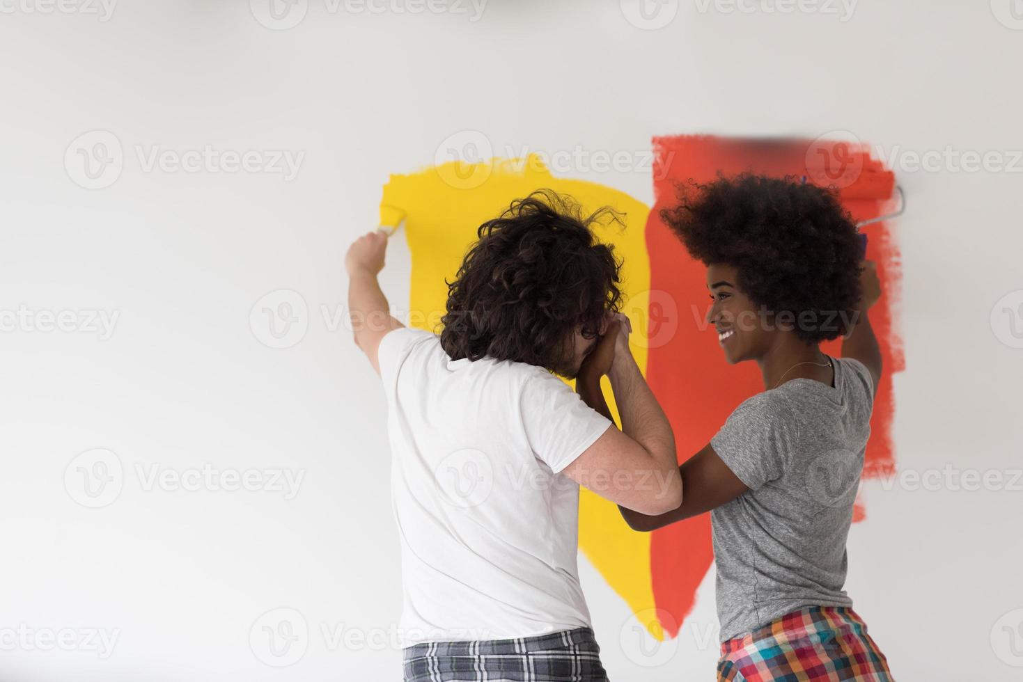 multiethnic couple painting interior wall photo