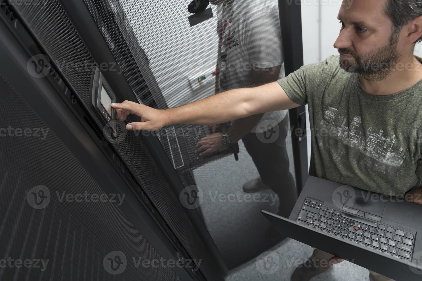 Technicians team updating hardware inspecting system performance in super computer server room or cryptocurrency mining farm. photo