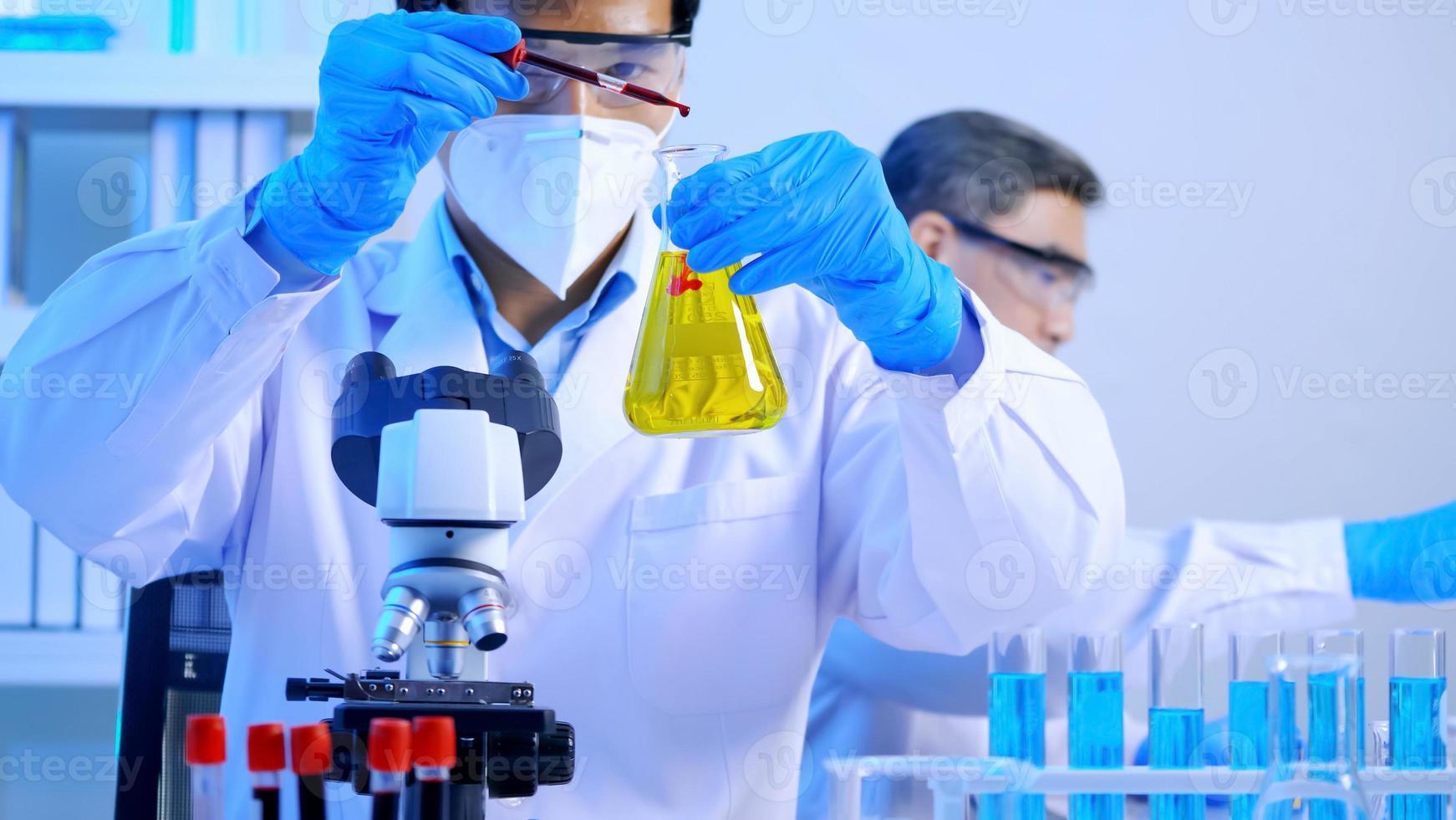 Asian scientist doing some research checking a liquid in a test flask at laboratory. photo