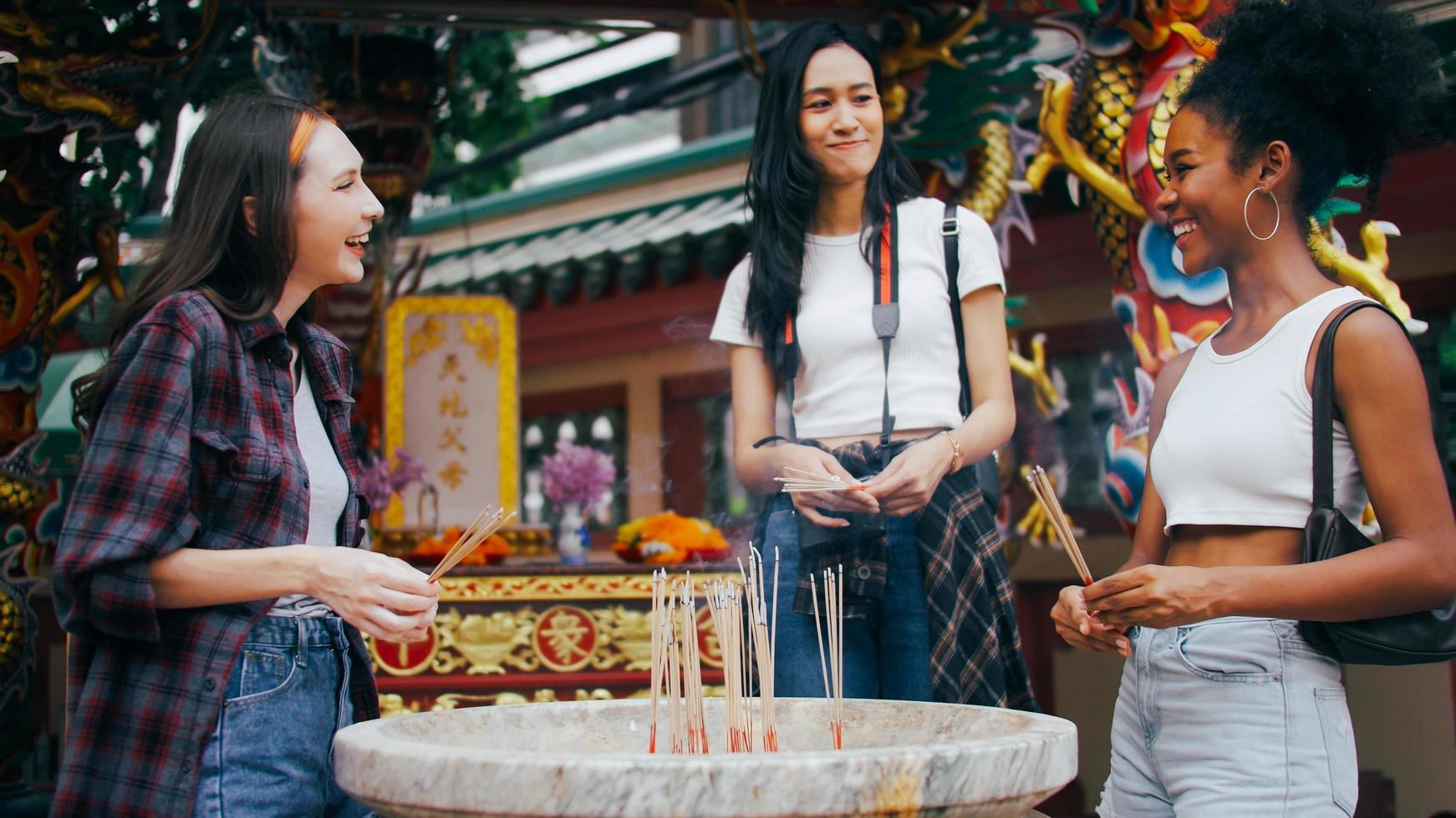 A group of multi-ethnic female friends praying at a Chinese shrine in Bangkok, Thailand. photo