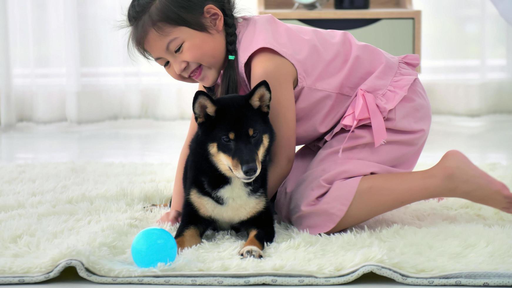 Asian little girl having fun playing with her dog at home. photo