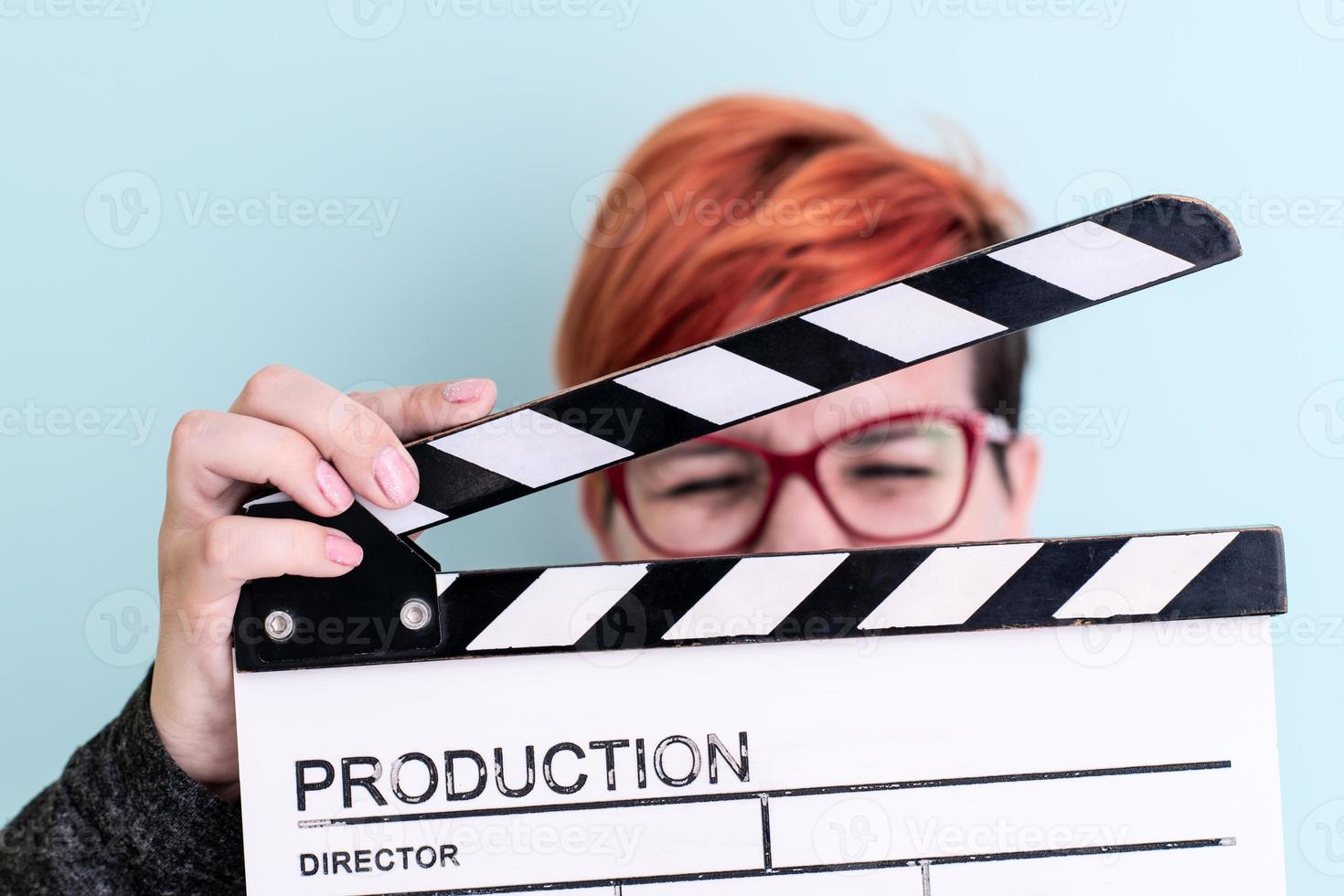 woman holding movie clapper against cyan background photo