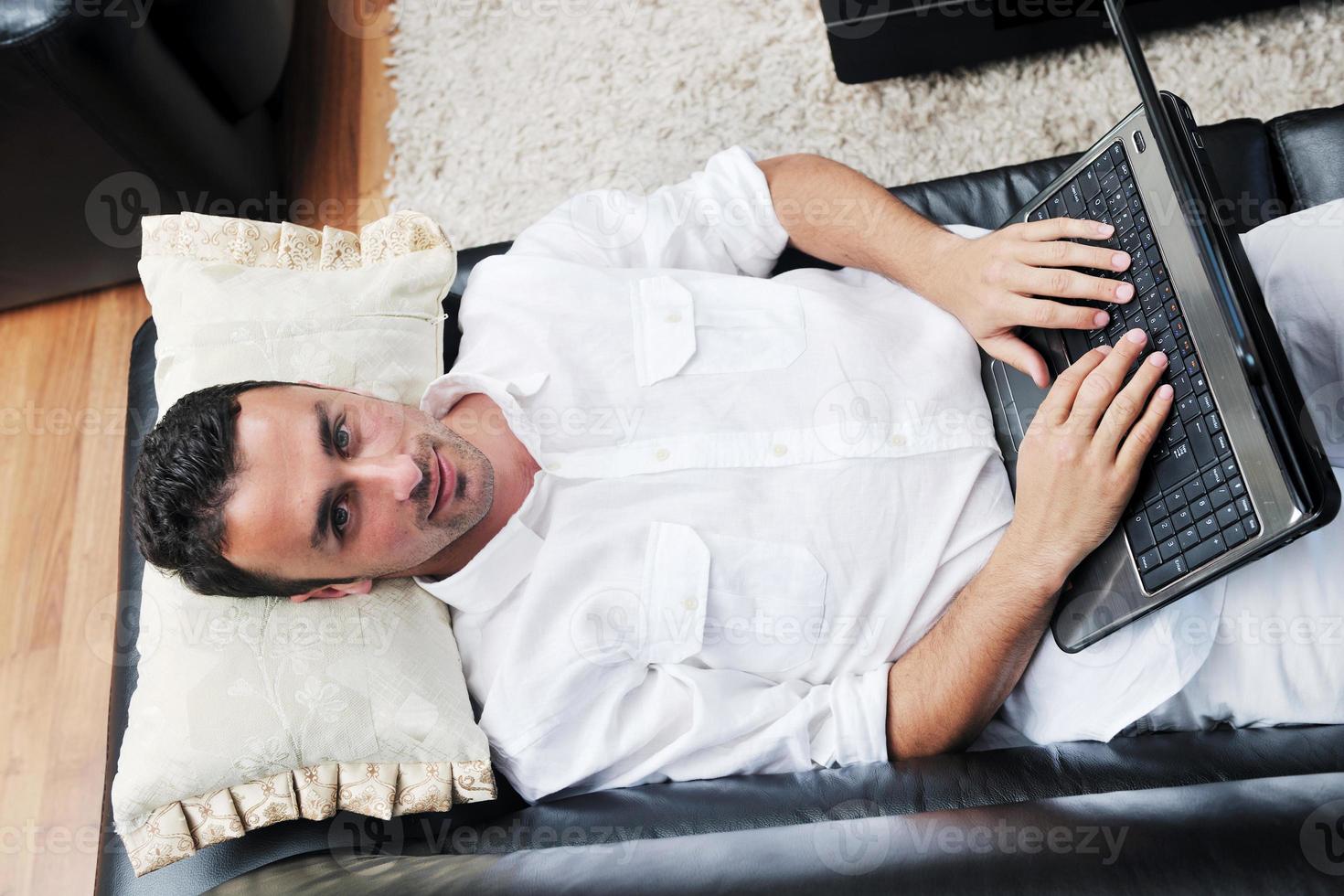 Portrait of a relaxed young guy using laptop at home photo