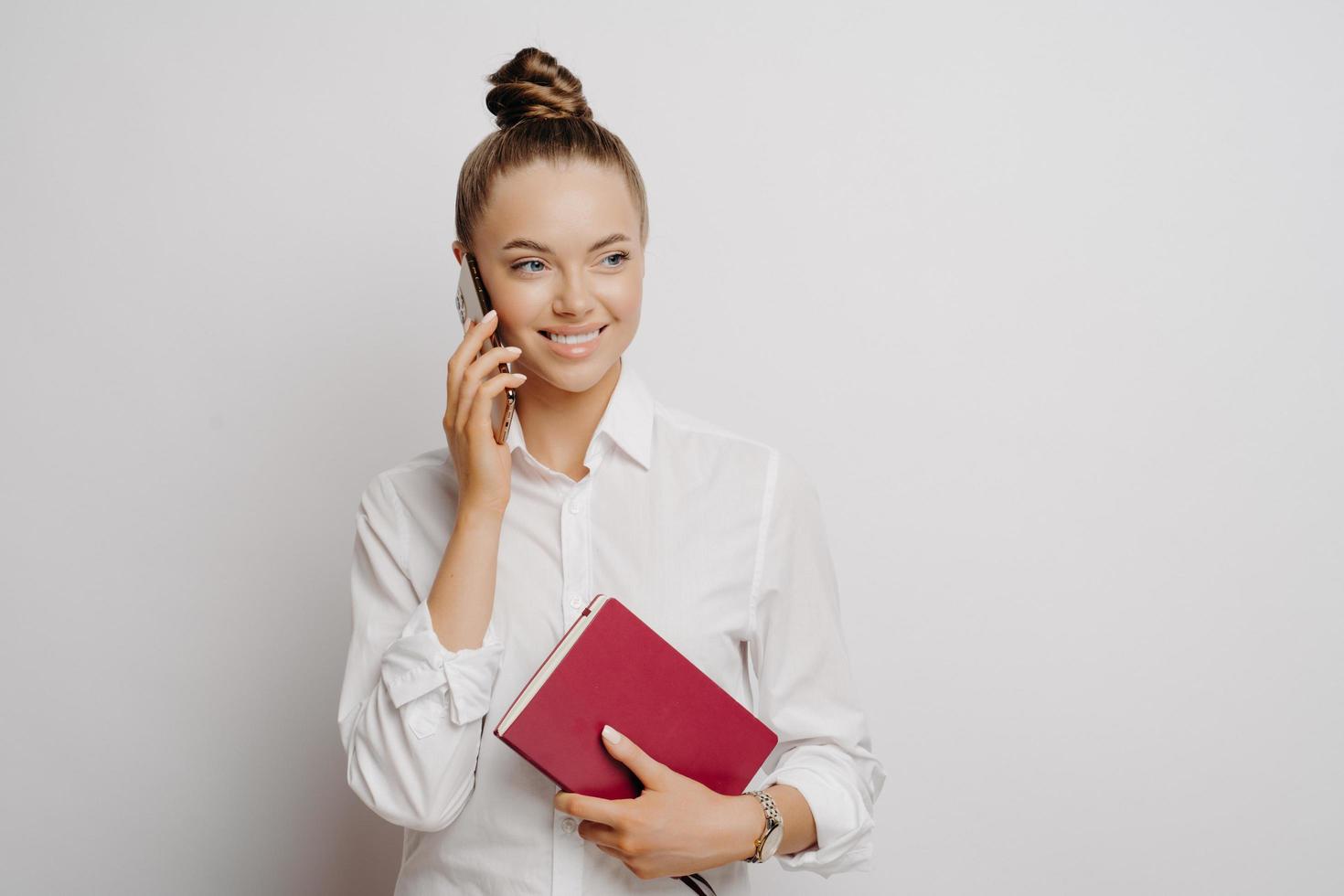 mujer de negocios feliz con camisa blanca con teléfono y portátil foto