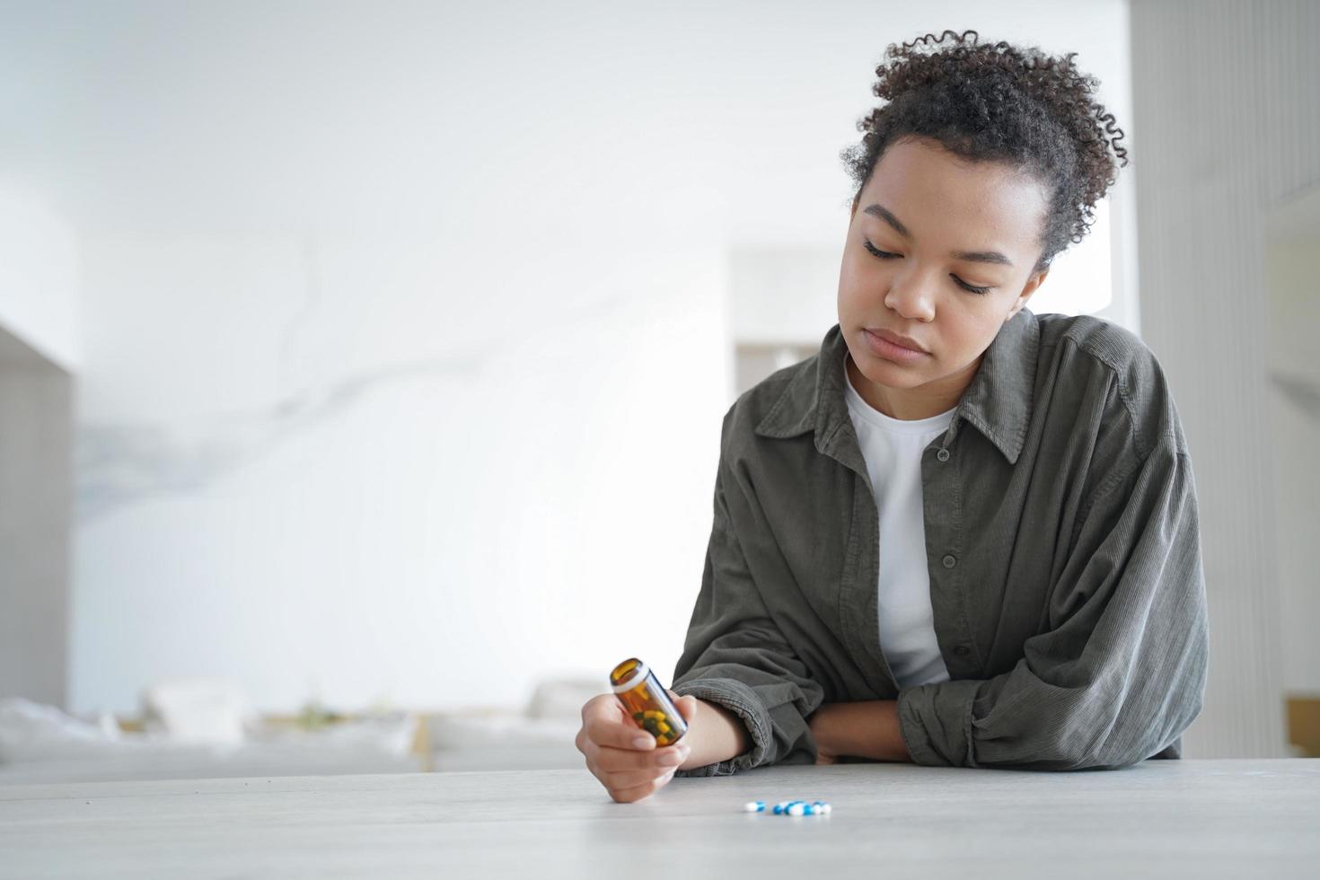 Pensive young woman holds bottle with medicines doubt whether to take pills. Healthcare. Copy space photo