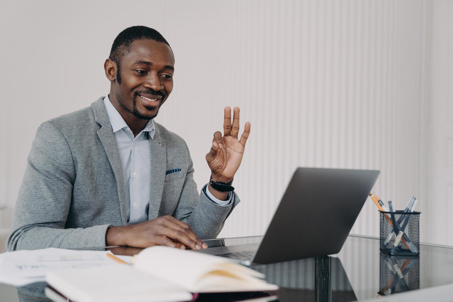 African teacher working online at home office and has lesson in sign language. E-learning concept. photo