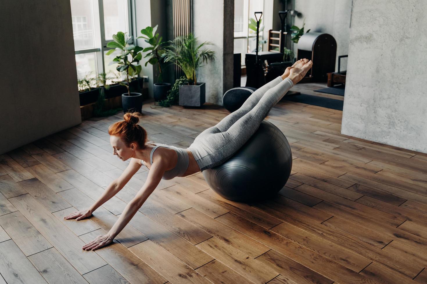 mujer delgada balanceándose en una pelota de ejercicio de estabilidad en un estudio de fitness foto