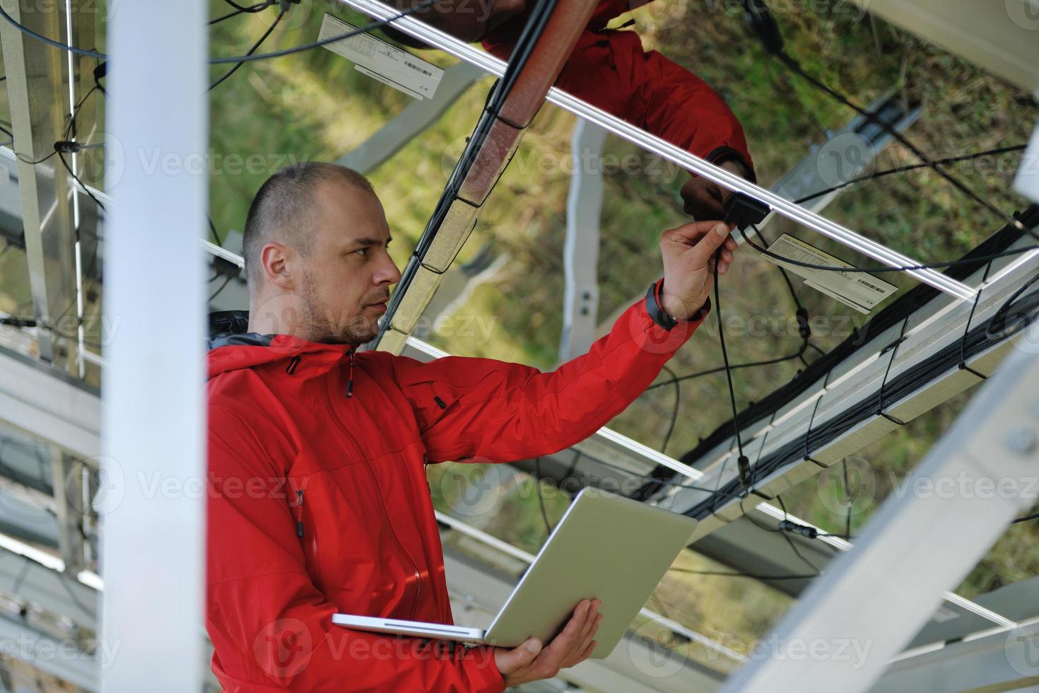 engineer using laptop at solar panels plant field photo