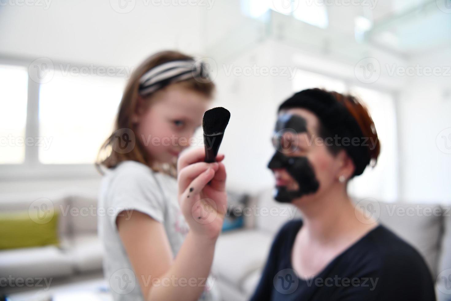 mother and daughter at home making facial mask beauty treatment photo