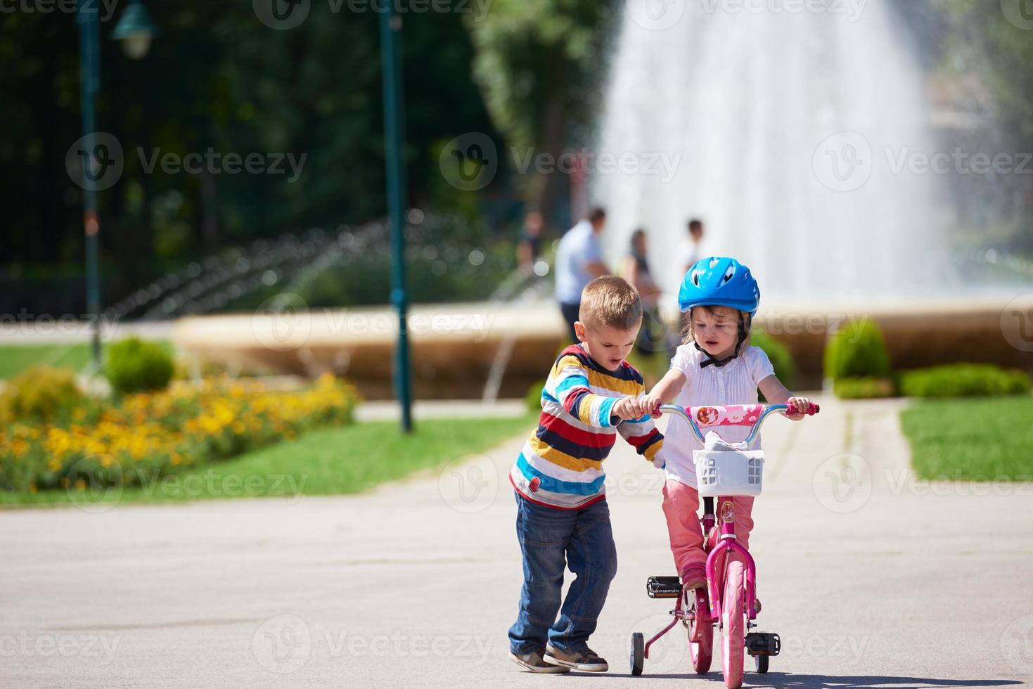 niño y niña en el parque aprendiendo a andar en bicicleta foto