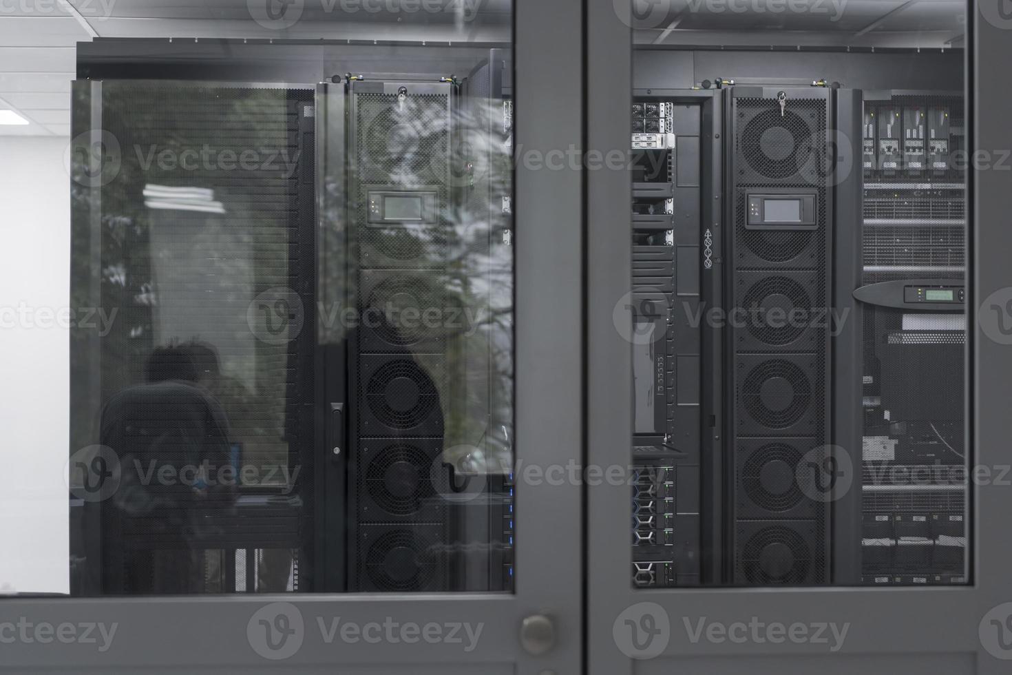 Software Engineer Working on a Laptop Computer in a Modern Server room. Monitoring Room Big Data Scientist in reflection of the entrance door. photo