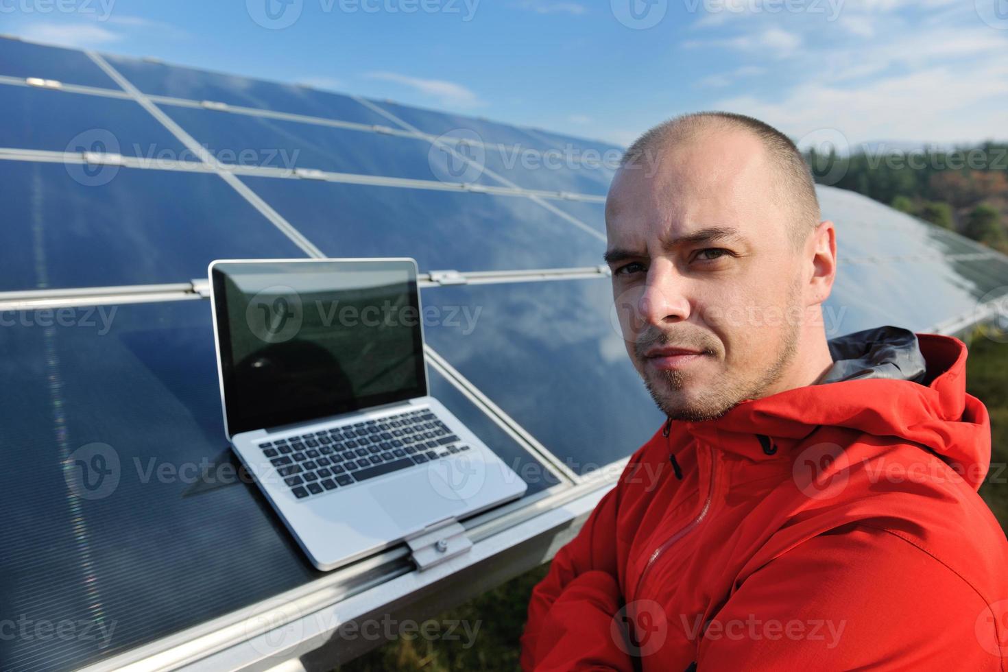 engineer using laptop at solar panels plant field photo