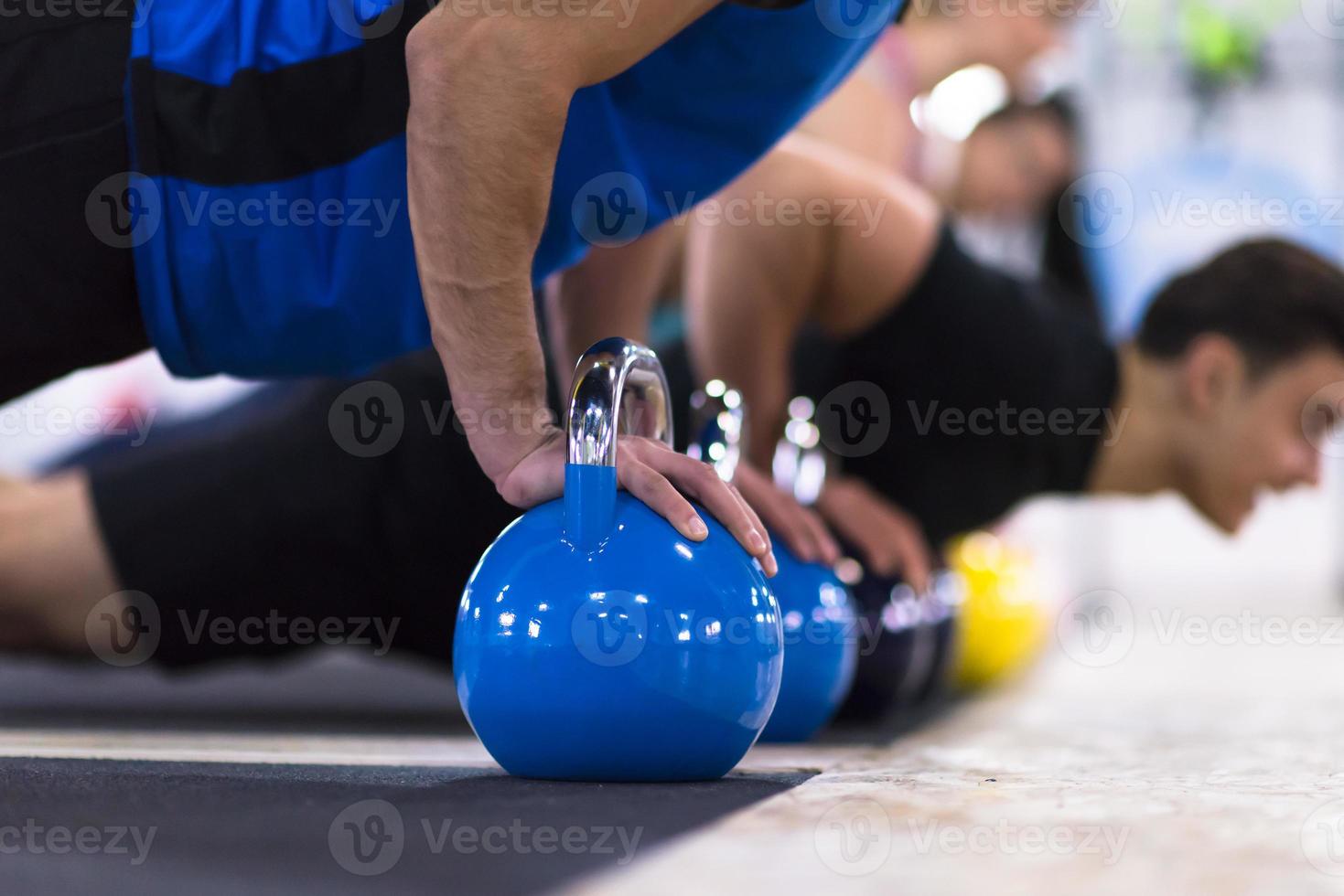 young athletes doing pushups with kettlebells photo