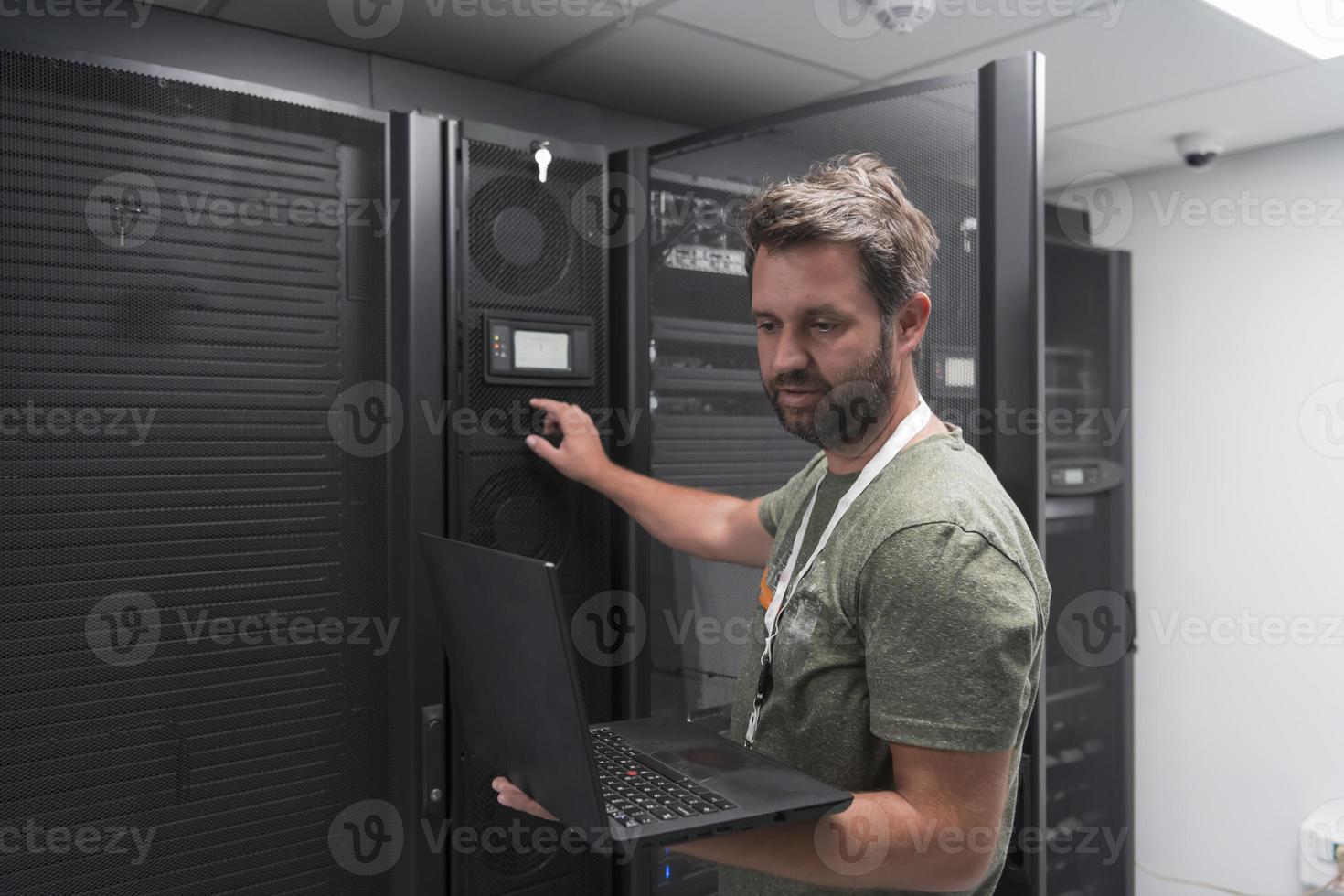 Data Center Engineer Using Laptop Computer Server Room Specialist Facility with Male System Administrator Working with Data Protection Network for Cyber Security or Cryptocurrency Mining Farm. photo