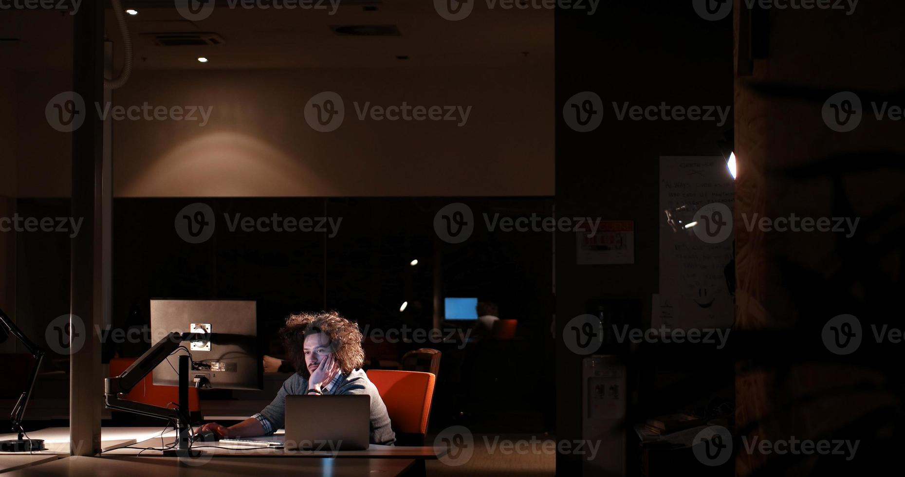 man working on computer in dark office photo