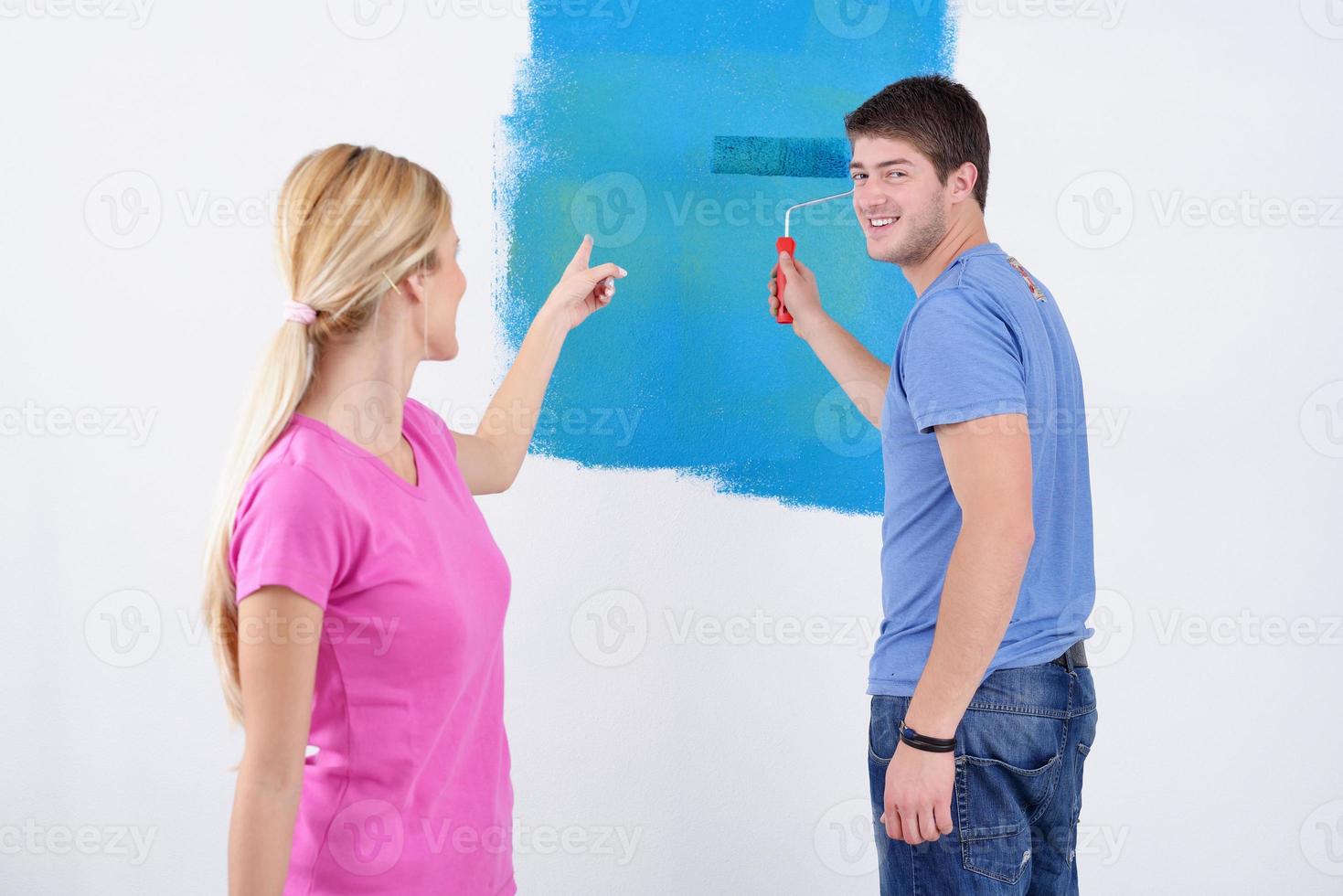 happy couple paint wall at new home photo
