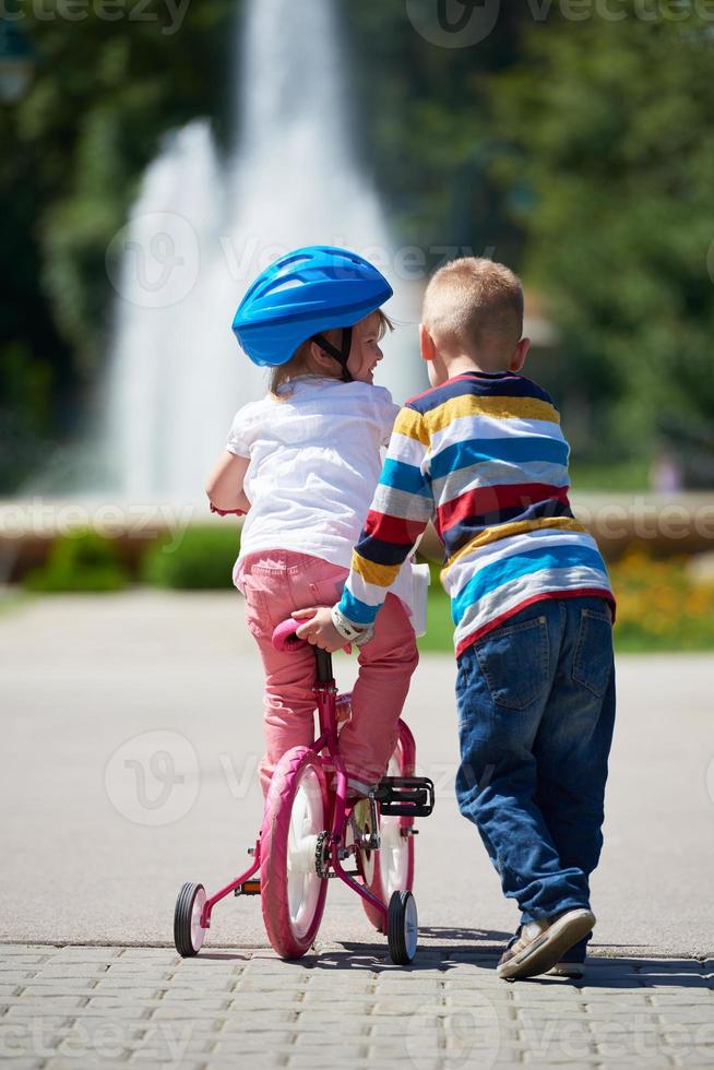 Boy and girl in park learning to ride a bike photo