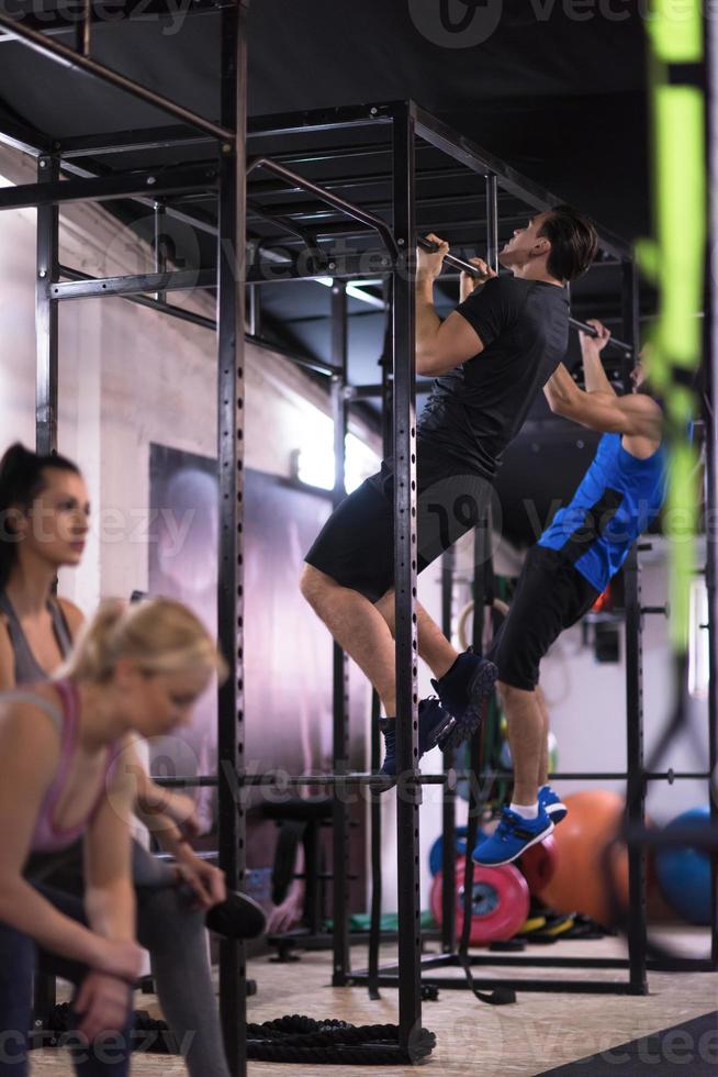 atletas jóvenes haciendo pull ups en la barra horizontal foto